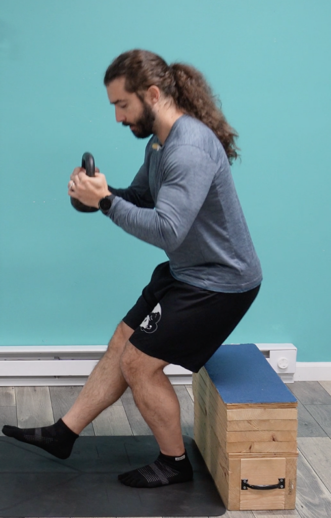 Dr. John demonstrating single leg box squats with weight for improving his hips